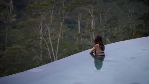 Woman in infinity pool with rainforest view 103 Stock Footage 264574271