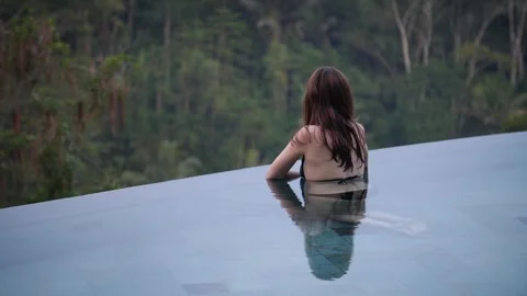 Woman in infinity pool with rainforest view 108 Stock Footage 264574276
