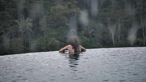 Woman in infinity pool with rainforest view 113 Stock Footage 264574285