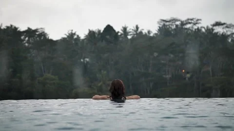 Woman in infinity pool with rainforest view 114 Stock Footage 264574286