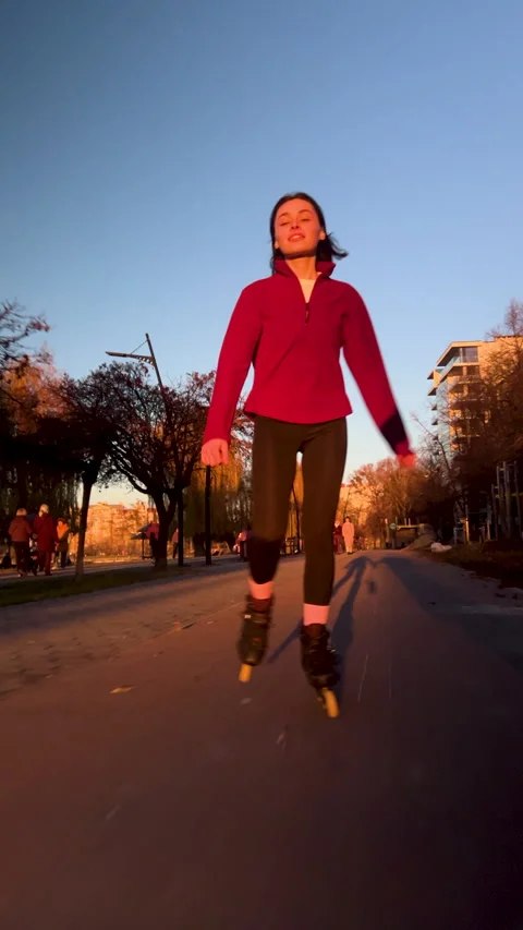 Woman on inline skates rides through city walkway at golden hour Stock Footage 346726169