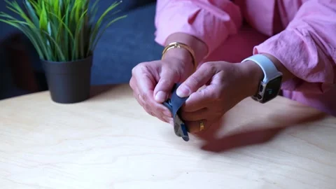 Woman Inserting Smart Tracker into Holder on Table Indoors Stock Footage 312799208