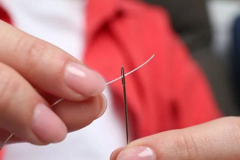 Woman inserting thread through eye of needle, closeup Stock Photos