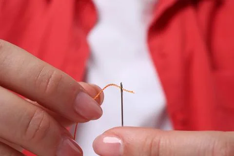 Woman inserting thread through eye of needle, closeup Stock Photos