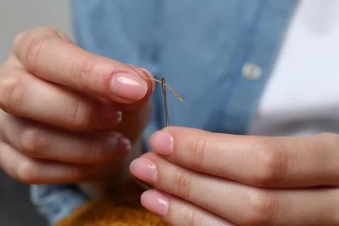 Woman inserting thread through eye of needle, closeup Foto stock