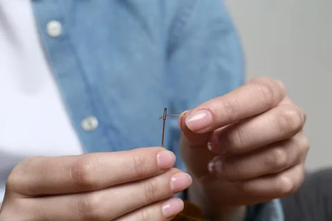 Woman inserting thread through eye of needle, closeup Foto stock