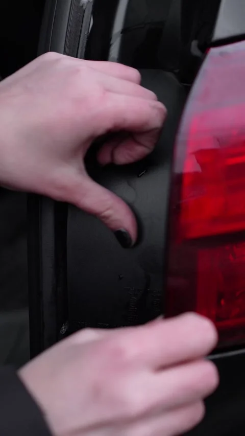 Woman inserts black plastic plug into taillight in car. self-repair of car, bulb Stock-Footage 327931403