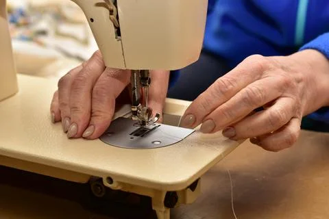 A woman inserts a bobbin of thread into a machine. 写真素材