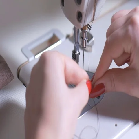 The woman inserts a light thread in a needle of the sewing machine Video stock 69736317