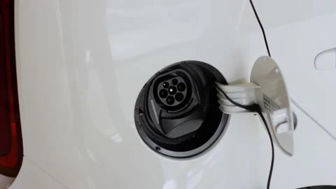 A woman inserts a plug into the car socket at the public charging station. An Stock Footage 134934349