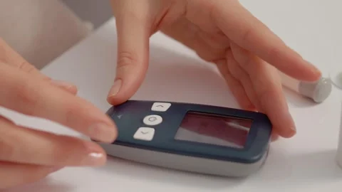 Woman inserts test strip into glucometer for blood sugar check Видео 346703484