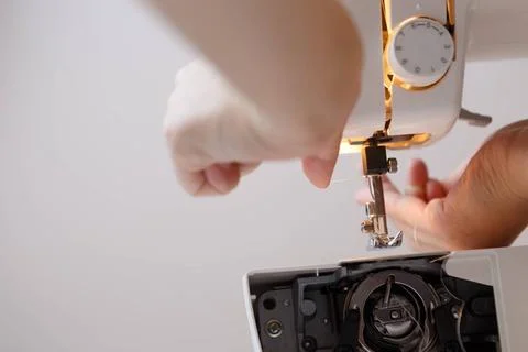 Woman inserts thread in sewing-machine Woman inserts thread in sewing mach... Foto stock
