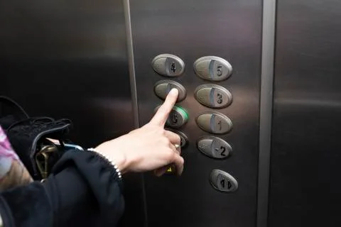 Woman inside an elevator pressing a button of the box Stock Photos