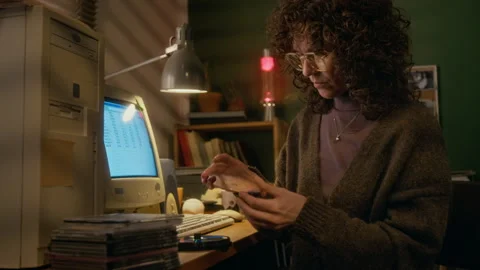 Woman Inspecting CD Disks while Working on Old-Fashioned Computer at Home Stock Footage 327234456