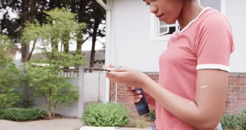 Woman inspecting, fitting drill bit into cordless drill chuck in backyard, Stock Footage 340981835