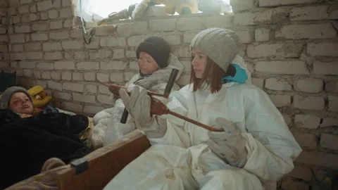 Woman Inspects Tool While Caring for Malnourished Children in Brick Shelter 스톡 동영상 347076438