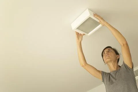 Woman installing a ceiling light. Fotos de archivo