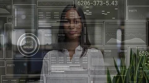 Woman interacting with digital interface in tech office displaying line graphs Stock Footage 307433743