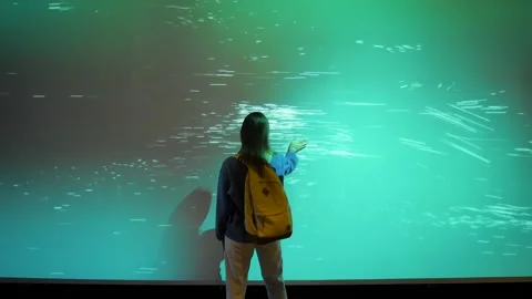 Woman interacting with immersive digital particles projection at exhibition Stock Footage 320891294