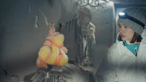 Woman investigating frozen objects inside abandoned icy house. An individual Stock Footage 346522300