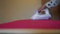 Woman ironing dark shocking pink fabric using a steam iron HD Footage