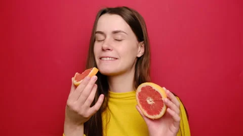 Woman isolated on studio red background eating fresh citrus grapefruit. Stock Footage 132527367