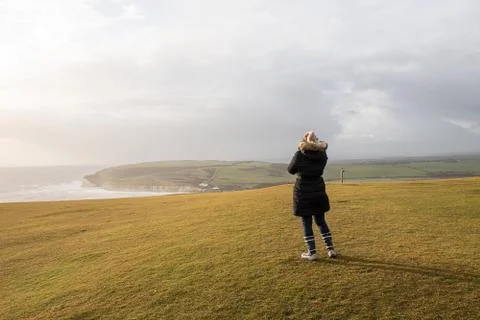 Woman in jacket standing on the cliffs Stock Photos