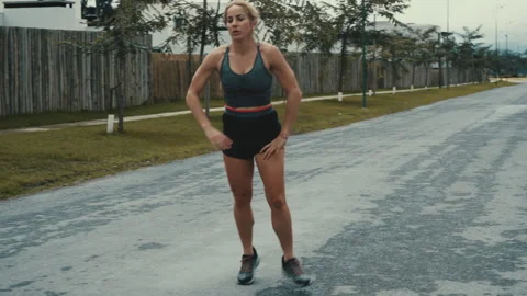 Woman jogging on quiet tree lined street past streetlights under cloudy sky Stock Footage 339622078