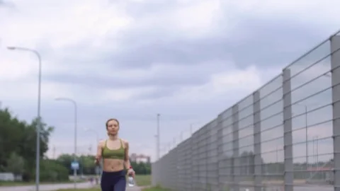 Woman in jogging suit drinks water Stock Footage