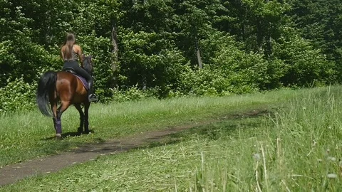 Woman jumping on a horse on a forest road Stock Footage 78092453