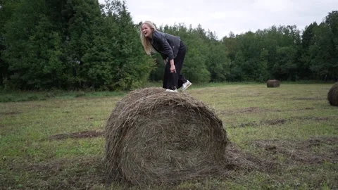 A woman jumps on a haystack in a field. Stock Footage 266780715