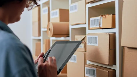 A woman keeps a record of parcels with barcodes prepared for shipment to cus 스톡 동영상 218617392