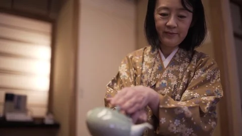 Woman in kimono pouring hot water into glass Stock Footage