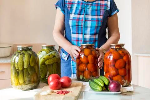 Woman in the kitchen next to the table. on the table are banks with pickled,  Stock Photos