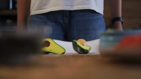 Woman kitchen preparing food, throws fresh avocado on the table with her hands Stock Footage 163411357