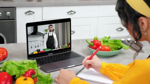 Woman in kitchen study remote culinary lesson listen chef, writes in notebook Stock Footage 162940174