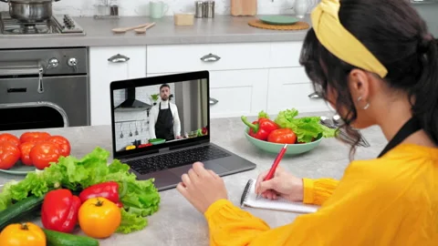 Woman in kitchen study remote culinary lesson listen chef, writes in notebook Stock Footage 230455552