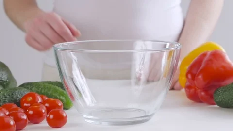 A woman at the kitchen table puts cherry tomatoes in a stacked bowl Stock Footage 101494930