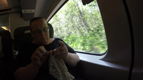 A woman is knitting a fabric while taking a long train ride from Bergen to Oslo Видео 79548792