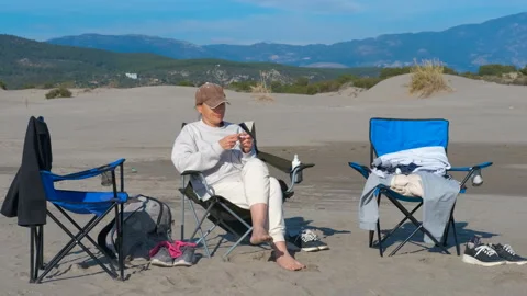 Woman knitting on a sandy beach while camping Stock Footage 329058620