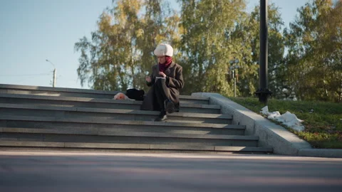 Woman knitting on stone steps outdoors with yarn and needles during daylight Stock Footage 346662353