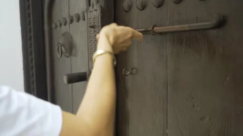 A woman knocks and opens an old traditional wooden door of a riad, in Bahrain Stock Footage 244548278