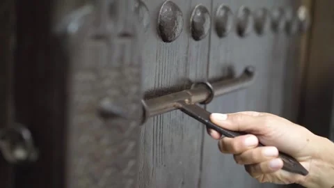 A woman knocks and opens an old traditional wooden door of a riad, in Bahrain Stock Footage 244944835