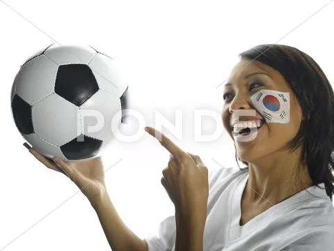 Woman with Korean flag painted on her face pointing at football, close-up Stock Photos