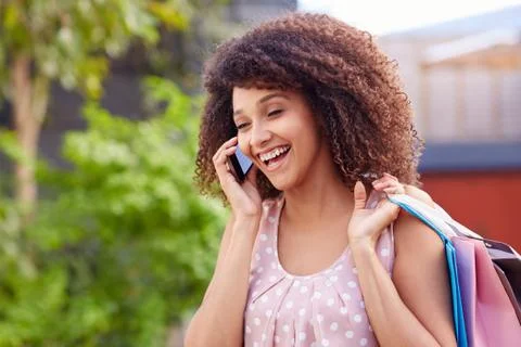 Woman laughin on her phone while out shopping Stock Photos