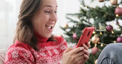 Woman laughing while using mobile phone on Christmas eve Stock Footage 129427345