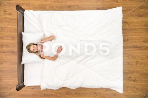 The woman lay on the bed and phone. View from above Stock Photos