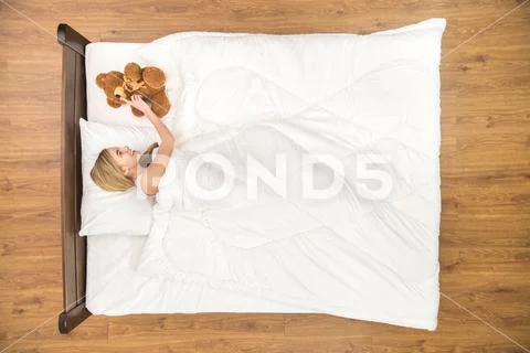 The woman lay on the bed with the soft toy. View from above Stock Photos