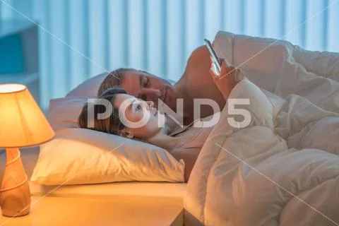 The woman lay with man and phone. Evening night time Stock Photos