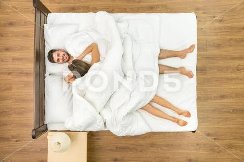 The woman lay near a man on the bed. View from above Stock Photos